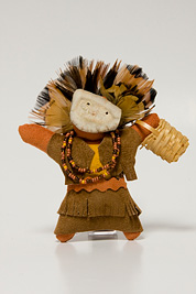 a small doll-like fetish with a headdress of feathers, beaded necklace, mask and dress made of leather.
